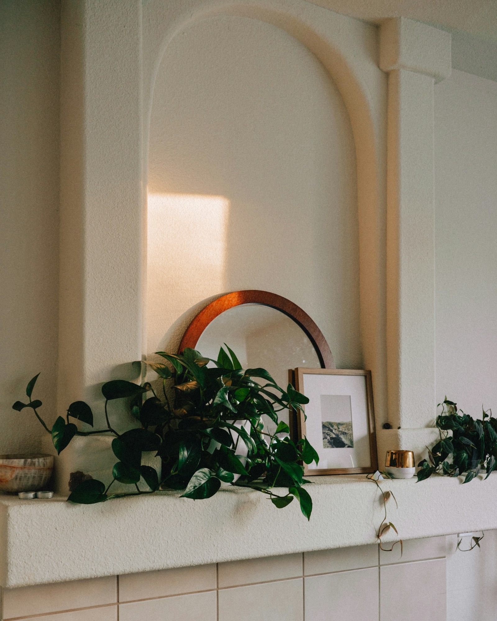 A warm shelf corner with trailing plants and framed art