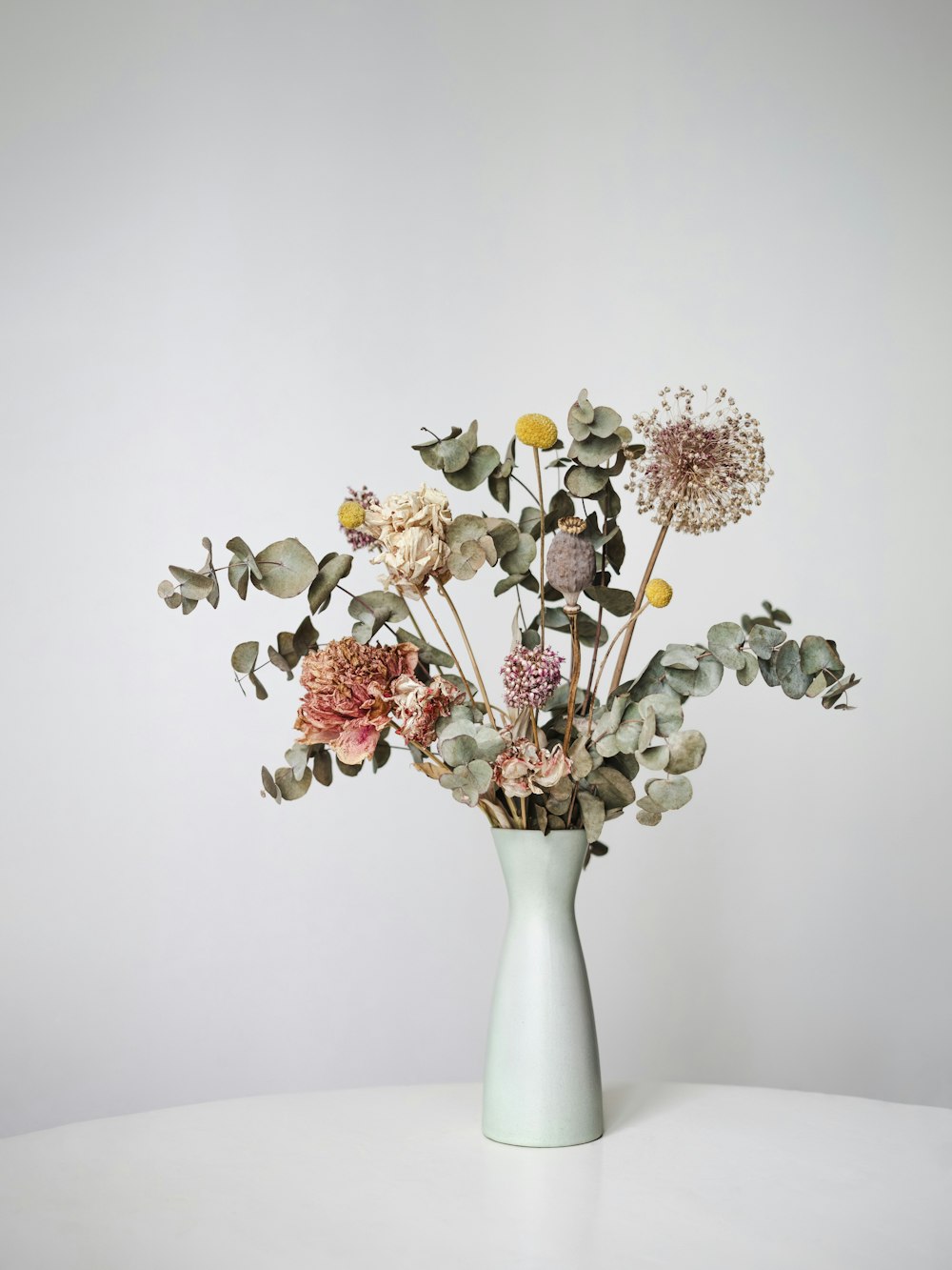 A dried flower bouquet in a pale vase